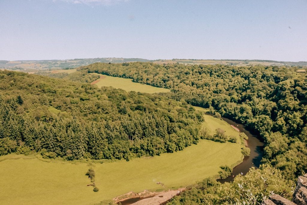 River winding through a green valley with lots of trees on a sunny day