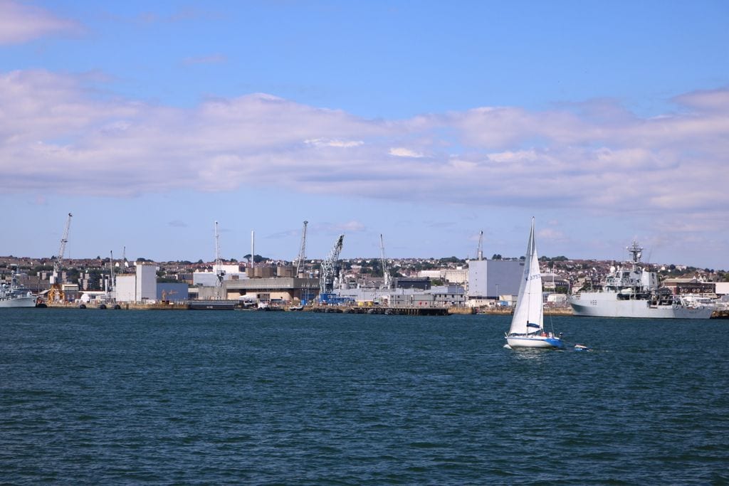 Blue water with sailboat and port in the background 