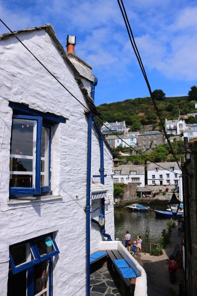 White pub with blue window frames and a hill with buildings in the background