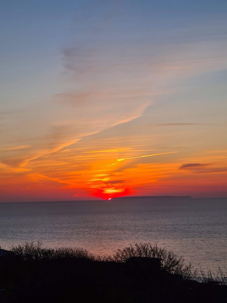 A sunset over the see with an island in the distance